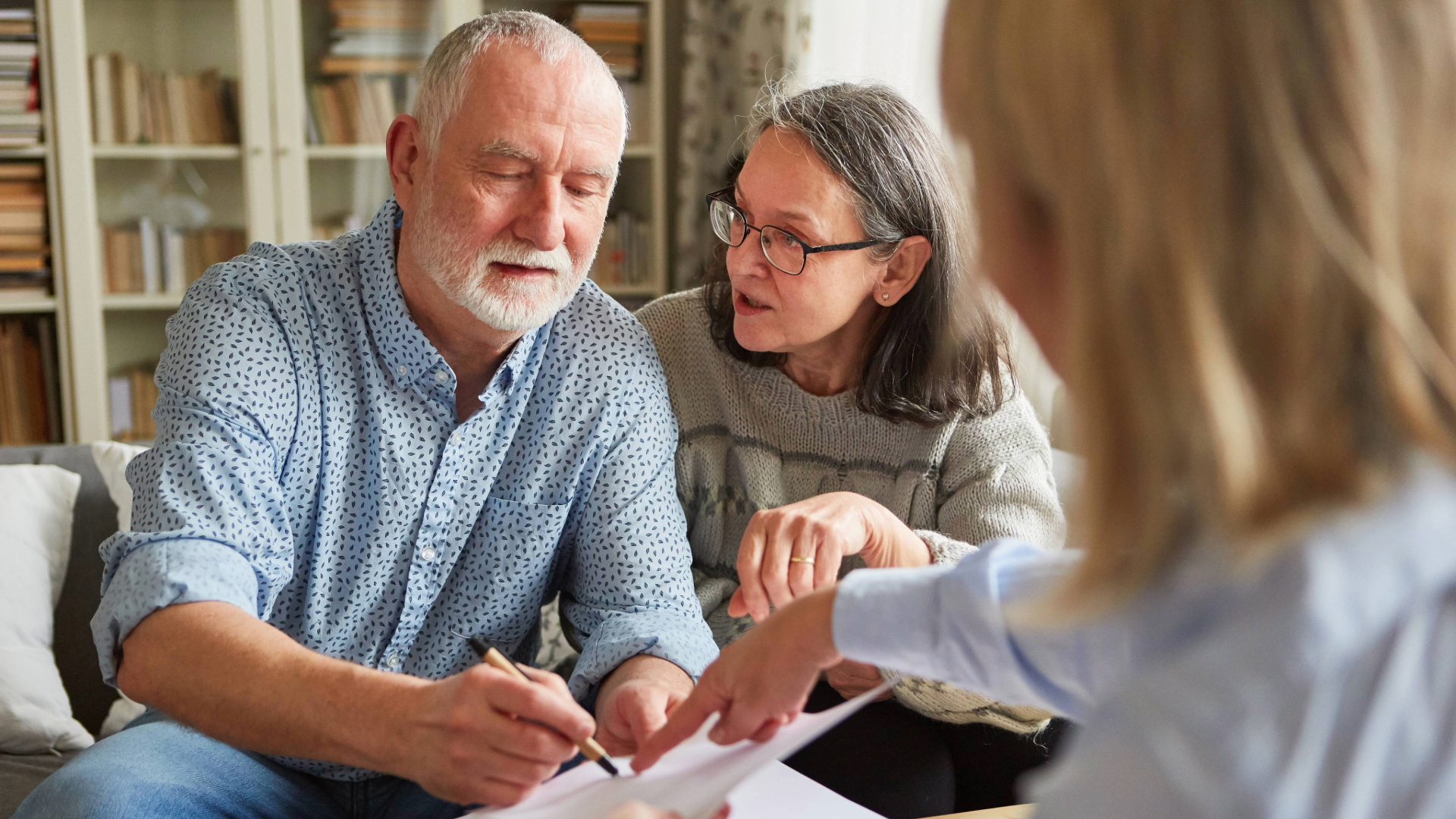 Older couple sign Lasting Power of Attorney form with solicitor.