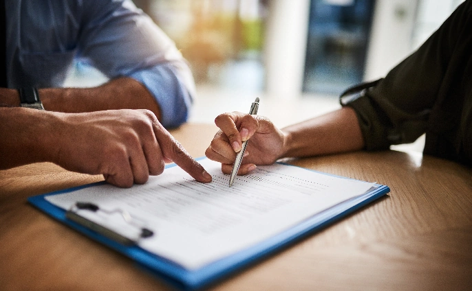 A woman signing a contract, symbolising a formal agreement such as the purchase of a house.